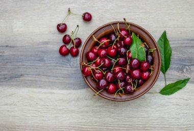 Ahşap arka planda taze kiraz tabağı. Taze kirazlar. Tatlı kirazlar. Yapraklı vişne kasesi.