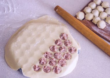 Geleneksel Rus pişmemiş pelmeni tahtada ve ev yapımı pelmeni malzemeleri beyaz masada. Pelmeni, ravioli veya etli hamur tatlısı yapma süreci. Uzayı kopyala Yan görünüm.