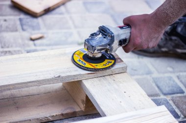 Eski ahşap tahtaları öğütücüyle onar. Bir marangoz ve marangozluk atölyesinde çalışan küçük bir büstiyer kapatıyoruz. Marangoz ahşapla çalışır. Yan görünüm.