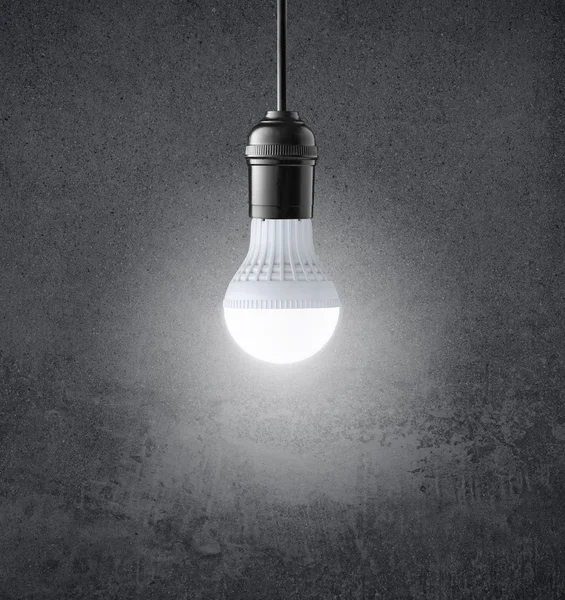 Glowing LED bulb on grunge wall — Stock Photo, Image