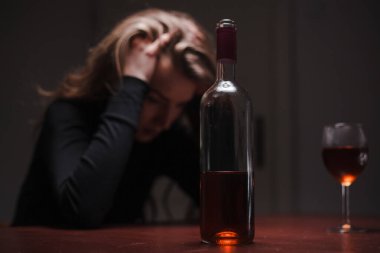 Depresyonda olan genç ve güzel bir kadın, alkol içiyor. Taciz ve alkolizm kavramı. Şişesi ve şarabı olan alkolik bir kadın..
