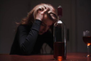 Depresyonda olan genç ve güzel bir kadın, alkol içiyor. Taciz ve alkolizm kavramı. Şişesi ve şarabı olan alkolik bir kadın..