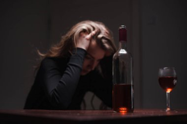 Depresyonda olan genç ve güzel bir kadın, alkol içiyor. Taciz ve alkolizm kavramı. Şişesi ve şarabı olan alkolik bir kadın..