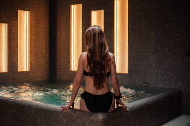 Güzel spa. Girdap banyosunun keyfini çıkaran genç bir kadının arka görüntüsü. Vücut bakımı kavramı. Güzellik ve vücut bakımı. Spa jakuzisinde dinlenen şehvetli genç bir kadın..