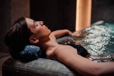 Vücut bakımı kavramı. Güzellik ve vücut bakımı. Girdap banyosundan hoşlanan genç bir kadın görüntüsü. Spa jakuzisinde dinlenen şehvetli genç bir kadın..