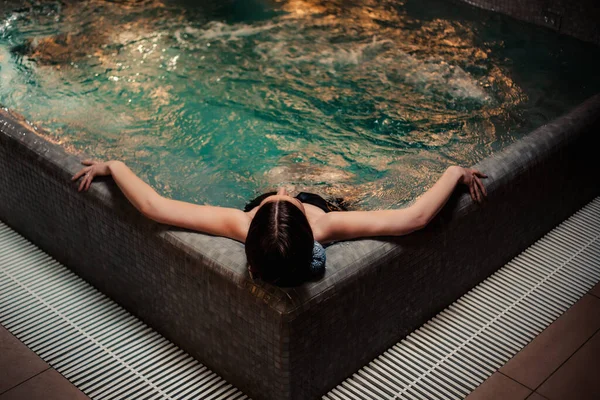 Vücut bakımı kavramı. Güzellik ve vücut bakımı. Girdap banyosundan hoşlanan genç bir kadın görüntüsü. Spa jakuzisinde dinlenen şehvetli genç bir kadın..