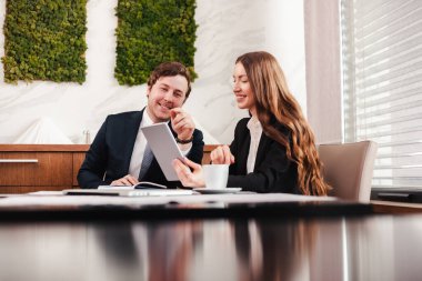 Genç iş kadını ve işadamı tablet ve belge kullanıyor, mali durumları hakkında konuşuyorlar..