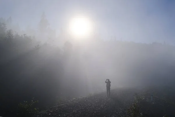 Paisagem nebulosa. Turista tirar fotos de manhã nevoeiro nascer do sol no alto das montanhas dos Cárpatos. Ucrânia . — Fotografia de Stock