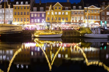Danimarka 'nın Kopenhag kentindeki Nyhavn limanındaki renkli eski evlerin önündeki teknelerin akşam manzarası. 
