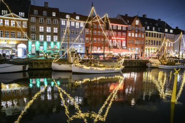 Danimarka 'nın Kopenhag kentindeki Nyhavn limanındaki renkli eski evlerin önündeki teknelerin akşam manzarası. 
