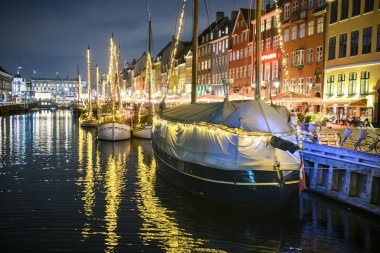 Danimarka 'nın Kopenhag kentindeki Nyhavn limanındaki renkli eski evlerin önündeki teknelerin akşam manzarası. 