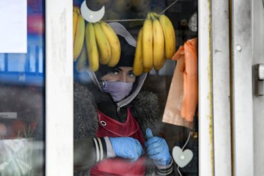 Mağazadaki satıcı, Ukrayna 'nın başkenti Kyiv' de Coronavirus COVID 19 'a karşı koruyucu bir önlem olarak koruyucu maske takıyor..