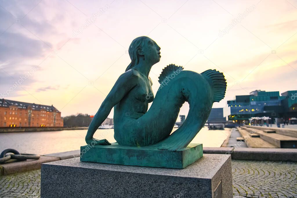 Evening view to Mermaid sculpture outside the Black Diamond Royal Danish Library in Copenhagen, Denmark. 