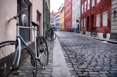 Danimarka 'nın tarihi merkezi Kopenhag' da dar bir sokakta renkli evlerin yanında duran bisikletler.