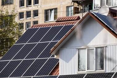 Kulübede çatıda güneş panelleri ve arkadaki apartman var.. 