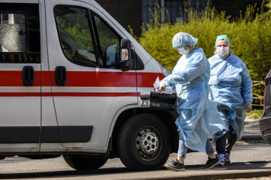 Koronavirüs COVID-19 'a karşı koruyucu giysiler giyen ambulans doktorları Ukrayna, Kyiv' de ambulans arabasının yanında. 