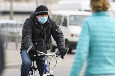 Koronavirüs COVID 19 'a karşı koruyucu maske takan bisikletçi Ukrayna' nın başkenti Kyiv 'de sokakta..