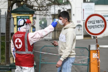 Koronavirüs COVID 'e karşı koruyucu ekipman uzmanı. 19 insan sıcaklığını ölçer. Kyiv, Ukrayna