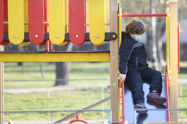 Koronavirüs COVID-19 'a karşı koruyucu maskeli çocuk Ukrayna, Kyiv' deki oyun alanında oynuyor.. 