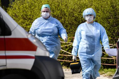 Koronavirüs COVID-19 'a karşı koruyucu giysiler giyen ambulans doktorları Ukrayna, Kyiv' de ambulans arabasının yanında. 