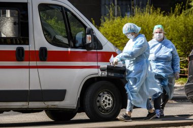 Koronavirüs COVID-19 'a karşı koruyucu giysiler giyen ambulans doktorları Ukrayna, Kyiv' de ambulans arabasının yanında. 