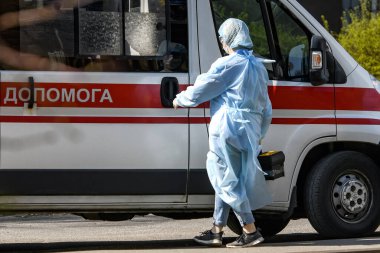 Koronavirüs COVID-19 'a karşı koruyucu giysiler giyen ambulans doktorları Ukrayna, Kyiv' de ambulans arabasının yanında. 