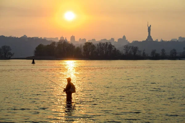 漁師はドニプロ川に立っています キエフの夕日と祖国の記念碑 — ストック写真