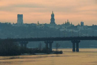 Paton köprüsü ve Kyiv Pechersk Lavra çan kulesi ve Lavra ortodoks kilise kubbeleri ve gün batımında manastır silueti.