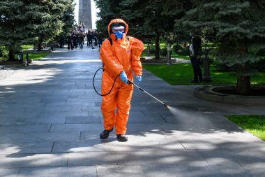 Koruyucu giysili adam COVID 19 'un yayılmasını önlemek için dezenfektan sıkar. Kyiv, Ukrayna Mayıs 2020