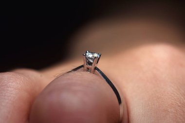 Parmağında beyaz altın elmas yüzük var. Alyans makro pozu..