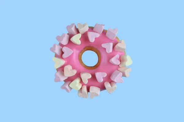 Rosa Donut mit Zuckerguss und Marshmallows-Herzen isoliert auf pastellblauem Hintergrund. süßer Donut. Ansicht von oben. — Stockfoto
