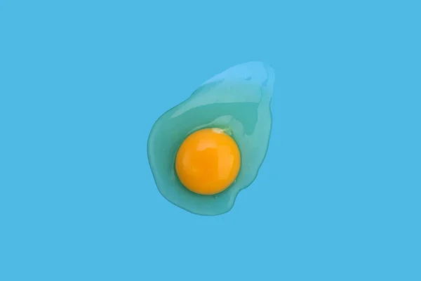 Gebrochenes Ei isoliert. Eiweiß und Eigelb auf blauem Hintergrund. Nahaufnahme — Stockfoto