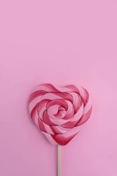 Kalp şeklinde lolipop pembe arka planda izole edilmiş. Kapat.