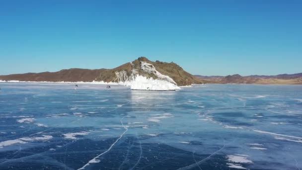 Παγωμένη λίμνη Baikal, ακρωτήριο Horin-Irgi του νησιού Olkhon. Όμορφο χειμερινό τοπίο με καθαρό λείο πάγο κοντά σε βραχώδη ακτή. Το διάσημο φυσικό ορόσημο της Ρωσίας. Μπλε διάφανος πάγος με βαθιές ρωγμές. — Αρχείο Βίντεο