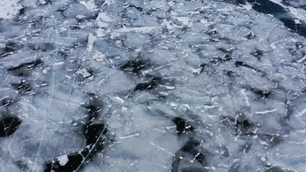 Lago Baikal congelado, cabo Horin-Irgi de la isla Olkhon. Hermoso paisaje de invierno con hielo suave y claro cerca de la costa rocosa. El famoso hito natural de Rusia. Hielo azul transparente con grietas profundas . — Vídeos de Stock