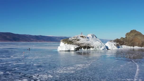 Donmuş Baykal Gölü, Olkhon Adası 'nın Horin-Irgi Burnu. Kayalık kıyıların yakınındaki pürüzsüz buzla güzel bir kış manzarası. Rusya 'nın ünlü doğal simgesi. Derin çatlakları olan mavi şeffaf buz. — Stok video