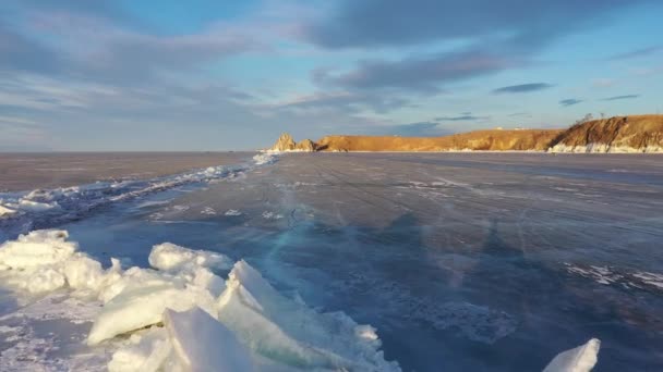 Frozen Lake Baikal, Cape Burhan Shaman rock of Olkhon Island. Turistas en el lago Baikal, caminando sobre el hielo del lago.. El famoso hito natural de Rusia. Hielo azul transparente con grietas profundas . — Vídeo de stock
