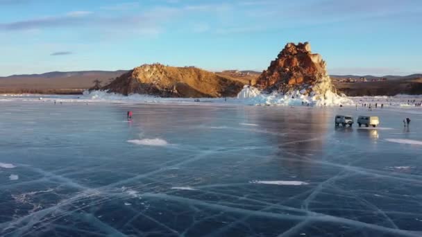 Lago Baikal congelado, Cabo Burhan Rocha xamã da Ilha Olkhon. Turistas no lago Baikal, andando sobre o gelo.. O famoso marco natural da Rússia. Gelo transparente azul com rachaduras profundas . — Vídeo de Stock