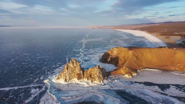 Lac Baïkal gelé, cap Burhan Rocher chaman de l'île Olkhon. Touristes sur le lac Baïkal, marchant sur la glace.. Le célèbre monument naturel de la Russie. Glace transparente bleue avec fissures profondes .