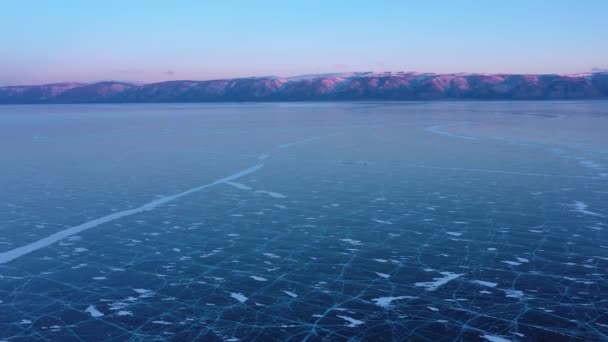 Lago Baikal ghiacciato, Vista aerea. Bellissimo paesaggio invernale con ghiaccio liscio chiaro. Famoso punto di riferimento naturale Russia. Ghiaccio trasparente blu con crepe profonde, vista dall'alto di un lago ghiacciato . — Video Stock