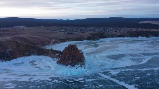 얼어붙은 바 이 칼 호수, 케이프 부르한 샤먼 바위가 올크 롱 섬의 쿠지 르 마을 근처에 있다. 바위가 많은 해안 근처에 맑고 부드러운 얼음 이 만 발 한 아름다운 겨울 풍경. 러시아 의유 명 한 천연 지형. — 비디오