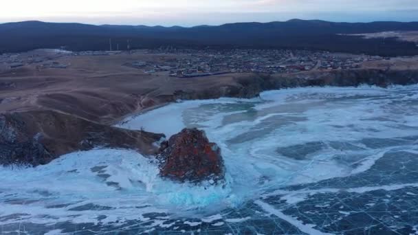 Lago congelado Baikal, cabo Burhan Shaman roca cerca de la aldea de Khuzhir, isla de Olkhon. Hermoso paisaje de invierno con hielo suave y claro cerca de la costa rocosa. Famoso monumento natural de Rusia . — Vídeos de Stock