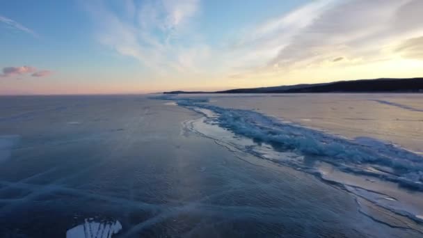 Lago congelado Baikal, lago Baikal hummocks. Hermoso paisaje de invierno con hielo suave y claro cerca de la costa rocosa. El famoso hito natural de Rusia. Hielo azul transparente con grietas profundas . — Vídeos de Stock