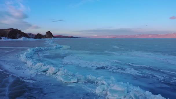 Fagyasztott Bajkál-tó, Bajkál-tó. Gyönyörű téli táj tiszta, sima jéggel a sziklás part közelében. A híres természeti mérföldkő Oroszország. Kék átlátszó jég mély repedésekkel. — Stock videók