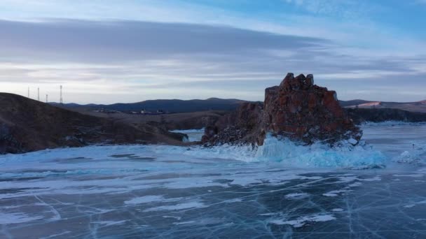 얼어붙은 바 이 칼 호수, 케이프부르 한 샤먼 섬의 바위. 바이칼 호수를 찾는 관광객들은 얼음 위를 걷고 있다. 유명 한 자연의 랜드마크 인 러시아. 깊은 틈 이 있는 푸른 투명 한 얼음. — 비디오