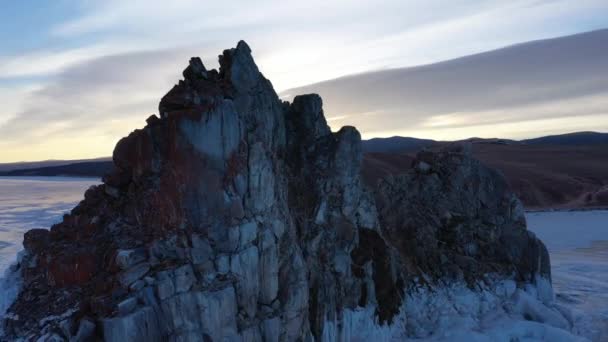 Frozen Lake Baikal, Cape Burhan Shaman rock of Olkhon Island. Tourists on lake Baikal, walking on the ice.. The famous natural landmark Russia. Blue transparent ice with deep cracks. — Stock Video