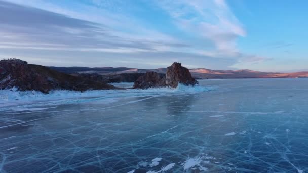 Frozen Lake Baikal, Cape Burhan Shaman rock of Olkhon Island. Turistas en el lago Baikal, caminando sobre el hielo.. El famoso hito natural de Rusia. Hielo azul transparente con grietas profundas . — Vídeo de stock