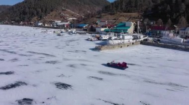 Hovercraft teknesi (Khivus) turist eğlencesi. Donmuş Baykal Gölü, hava manzaralı. Pürüzsüz buzla güzel bir kış manzarası. Rusya 'nın ünlü doğal simgesi. Derin çatlakları olan mavi şeffaf buz