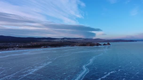 Mražené jezero Bajkal, mys Burhan Shaman rock na ostrově Olkhon. Krásná zimní krajina s jasným hladkým ledem u skalnatého pobřeží. Slavný přírodní památník Ruska. Modrý průhledný led s hlubokým krabem — Stock video