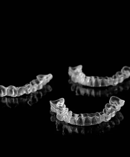 Invisible orthodontics cosmetic brackets on black background.